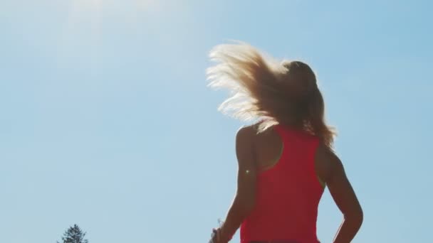 Silhouette d'une athlète féminine au stade pétrissant sur fond de ciel bleu. Réchauffement au stade avant le début des compétitions d'athlétisme. — Video