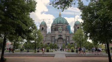 Berlin, Almanya, 25 Mayıs 2025: Güneşli bir günde turistlerle Berlin Katedrali. Berlin Katedrali 'nin etrafı ağaçlar ve turistlerle çevrili, Almanya' daki büyük mimari ve kültürel önemini gözler önüne seriyor..