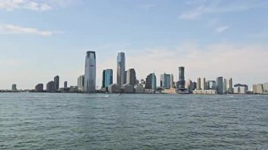 Hudson Nehri 'nin karşısındaki modern Jersey şehrinin silueti. Jersey Citys 'in panoramik manzarası gökyüzü açık mavi gökyüzünün altında Hudson Nehri' ne yansıyan gökdelenli gökdelenler.