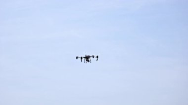 Quadcopter İHA 'sı gökyüzünde uçuyor, pervaneler dönüyor, insansız hava aracı teknolojisi havada asılı duruyor, fotoğraf ve gözetim için modern ekipmanlar var..