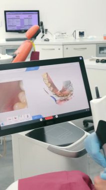 Diş hekimi CEREC tarayıcısını kullanarak hastaların dişlerini tarıyor. Modern dişçilik. Diş hekimi hastaların dişlerini taramak için 3 boyutlu diş içi tarayıcı kullanır..