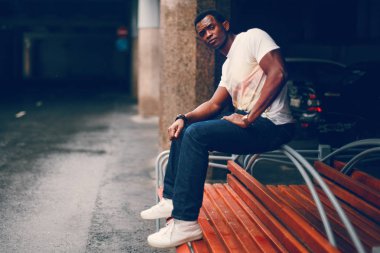 Bankta tek başına oturan siyah adam