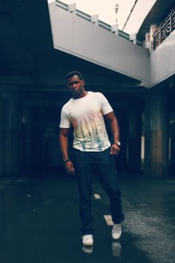 Koyu renkli bir tünelde beyaz tişörtlü siyah adam
