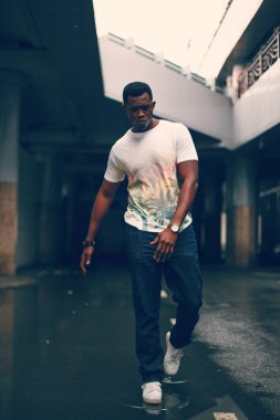 Koyu renkli bir tünelde beyaz tişörtlü siyah adam