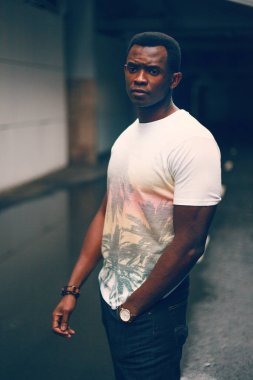 Koyu renkli bir tünelde beyaz tişörtlü siyah adam