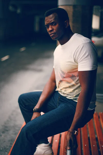 Bankta tek başına oturan siyah adam