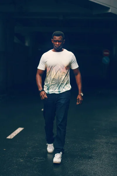 Koyu renkli bir tünelde beyaz tişörtlü siyah adam