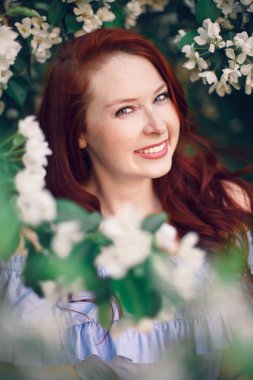 Çiçek açan elma ağacında poz veren kızıl saçlı bir model..
