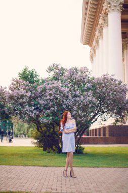 Kızıl saçlı manken yazın çiçek açan leylakların içinde poz veriyor..
