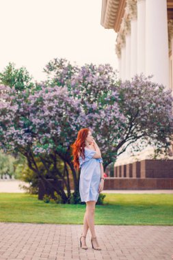 Kızıl saçlı manken yazın çiçek açan leylakların içinde poz veriyor..