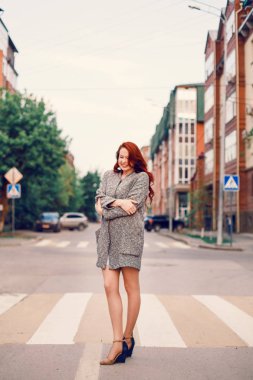 Sokakta gün batımının arka planında poz veren kızıl saçlı bir manken..