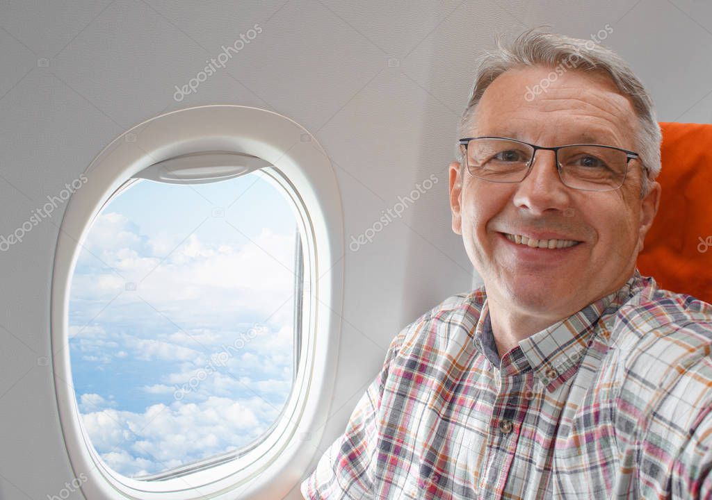 Middle aged handsome man sitting in airplane