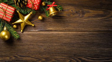 Köknar ağacı dalları çam koni jingle bell ve kırmızı hediye kutuları ile Noel köşede kahverengi rustik kurulu.