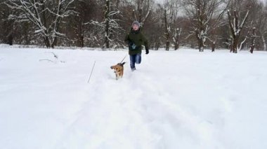 Beagle köpek çalışan çocuk kameraya doğru yüksek kar üzerinden