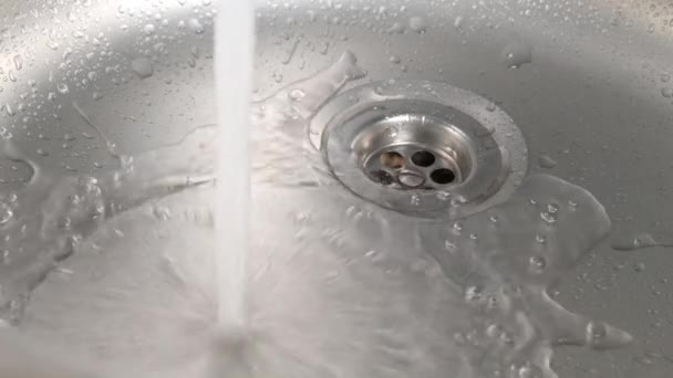 Vatten som rinner från en kran i en diskho. — Stockvideo