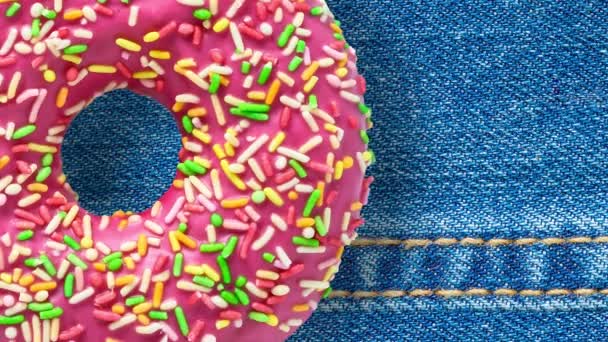 Donut rosa girando no fundo azul jeans — Vídeo de Stock