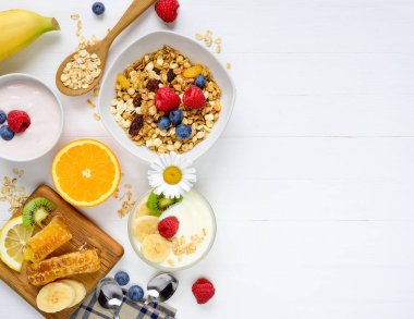 Kahvaltı müsli, granola, yoğurt, meyve, meyve ve ballı Beyaz ahşap zemin üzerinde. Düz yatıyordu boş alan