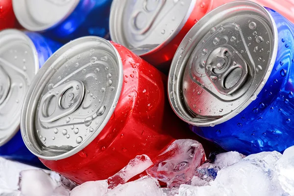 Canettes de soda rouges et bleues sur glace avec gouttelettes de condensation — Photo