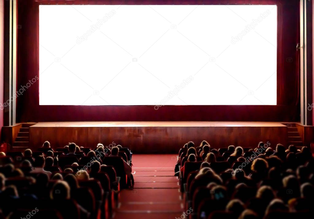 People in the cinema auditorium with empty white screen.