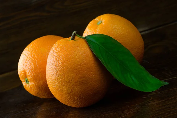 Laranjas frescas em um fundo de madeira escura . — Fotografia de Stock