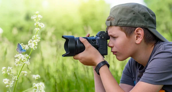 Junge hält Digitalkamera und schießt Schmetterling auf die Wildblume — Stockfoto