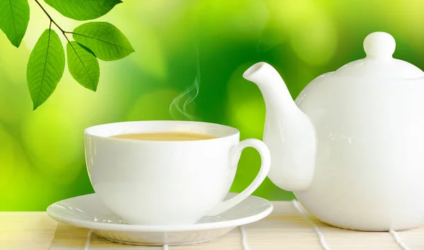 Taza de té verde y tetera de cerámica blanca sobre mesa de madera . — Foto de Stock