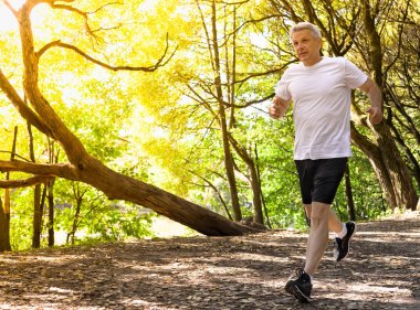 Sonbahar parkında çalışan aktif orta yaşlı adam