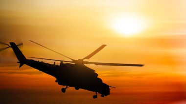 Gün batımında gökyüzünde uçan helikopter silueti.