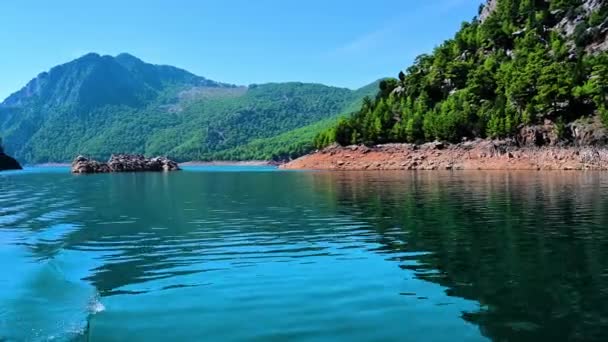 Seguimiento de disparo desde una popa barco flotando en un hermoso lago en las montañas. Vídeo 4K — Vídeo de stock