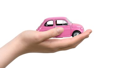 Beyaz arka planda pembe oyuncak araba ve kadın eli. Araba satın alma kavramı