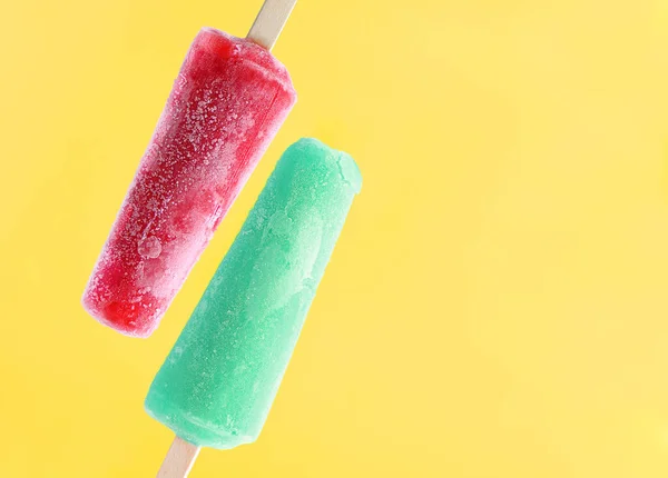 El helado brillante se pega sobre un fondo amarillo . — Foto de Stock