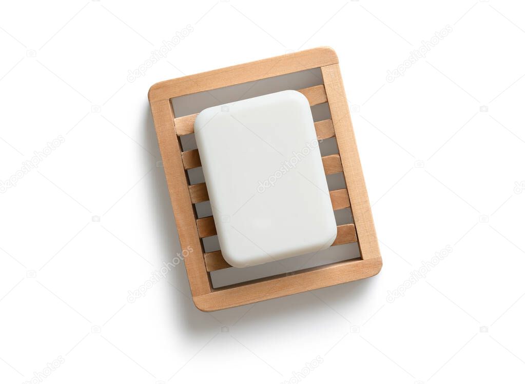White bar of soap on wooden soap dish isolated on a white background. Directly above.