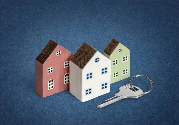 Casas em miniatura com chave de casa no fundo azul — Fotografia de Stock