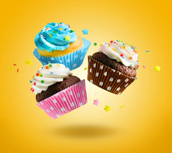 Cupcakes voando sobre fundo amarelo. — Fotografia de Stock