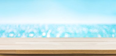 Boş ahşap masa üstü, bulanık mavi gökyüzü ve deniz bokeh arkaplanı.