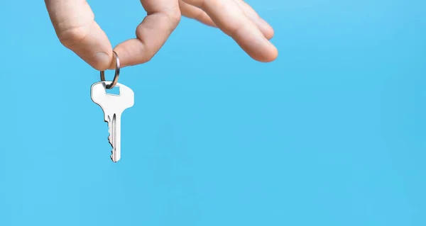 Hand with home key on blue background.