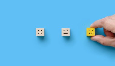 Müşteri eli mavi arka planda gülen yüzlü ahşap bloğu seçti..