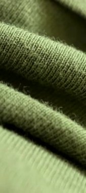 Soft green knit fabric that beautifully showcases its intricate textures and craftsmanship vertical background
