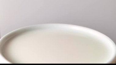 Taze süt damlası düşüyor ve süt kabına sıçrıyor. Yavaş çekim halkaları ve dalgalanma