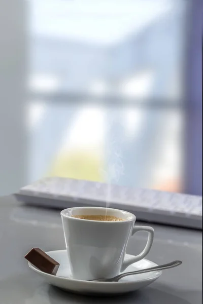 Чашка кофе на столе с компьютерной клавиатурой для бизнес-концепции с большим фоном окон — стоковое фото