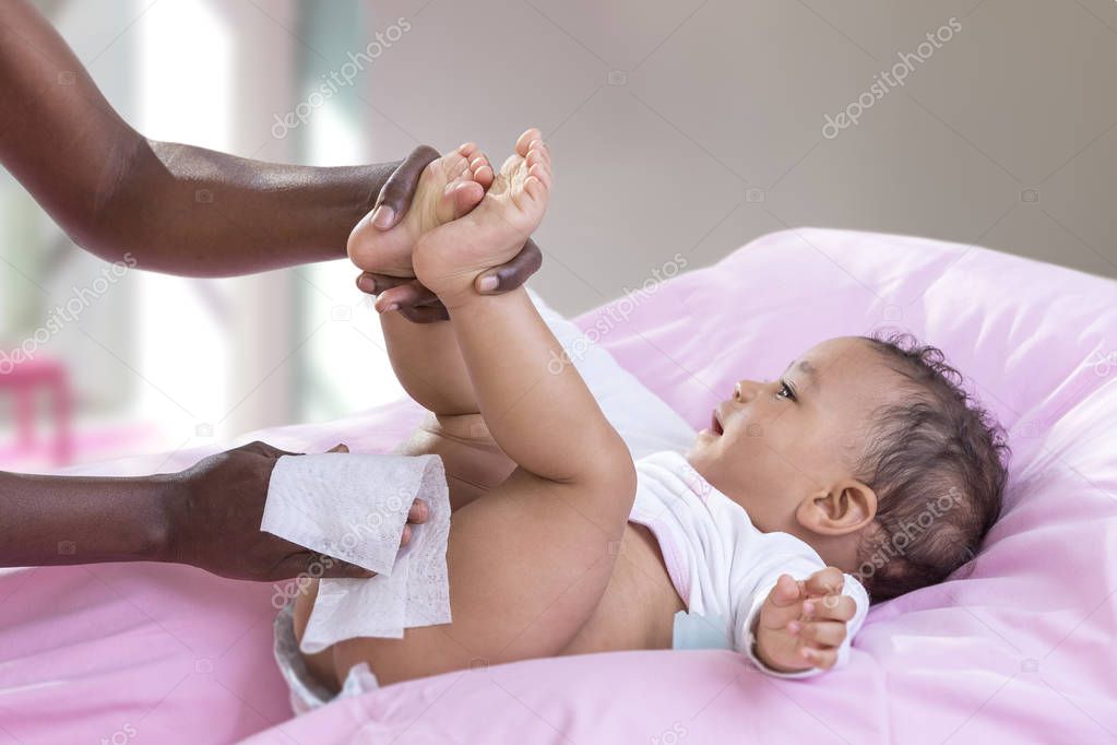 Hygiene Child. Side view portrait of a happy Afrriican, American, mother changing diaper to her baby