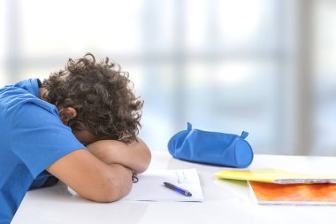 Bunalmış okul çocuğu. Bıkkın ve yorgun genç çocuk odasında, Masa üzerinde ödev gibi görünüyor sleepinp
