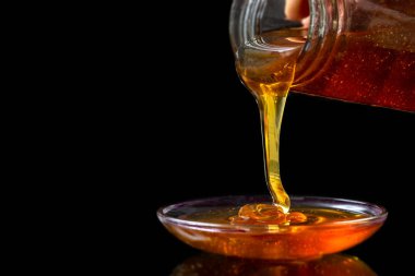 Altın sıvı Organik Bal siyah bacgrond üzerinde kavanoz dan dökülen