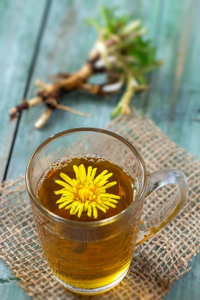 Dandelion tea background, herbal remedy. Dandelion tea, flower, leaves and root on wooden background. — Stock Photo, Image