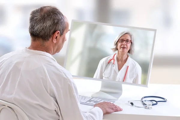 Concepto de telemedicina, Doctor sentado en el hospital, con portátil, teniendo una llamada en línea con un paciente que muestra un dispositivo de ablet — Foto de Stock