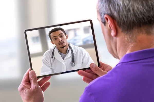 Telemedicine concept, Doctor sitting at hospital, with laptop, having an online call with a patient showing a ablet device