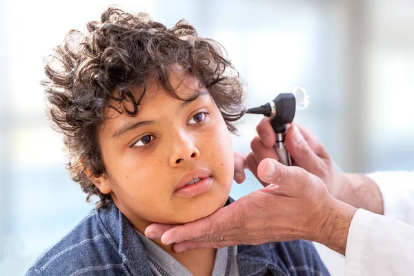 Smiling doctor examining little boys ears with otoscope at hs offciee — Stock Photo, Image