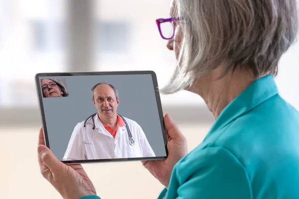 Conceito de telemedicina, médico sentado no hospital, com laptop, ter uma chamada on-line com um paciente mostrando um dispositivo ablet — Fotografia de Stock