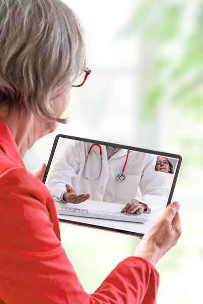 Concepto de telemedicina, Doctor sentado en el hospital, con portátil, teniendo una llamada en línea con un paciente que muestra un dispositivo de ablet — Foto de Stock