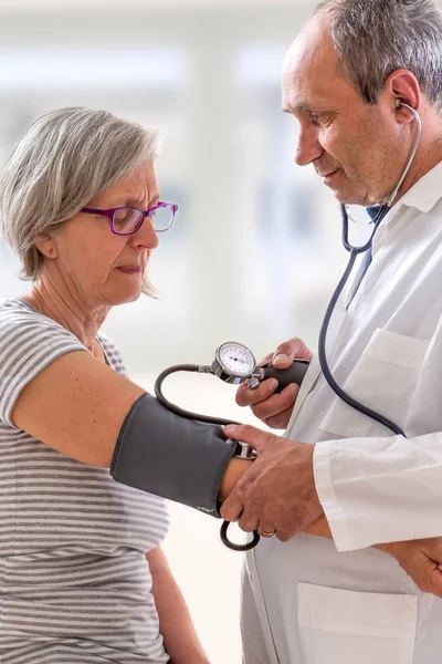 Un médico toma la presión arterial de un paciente . — Foto de Stock